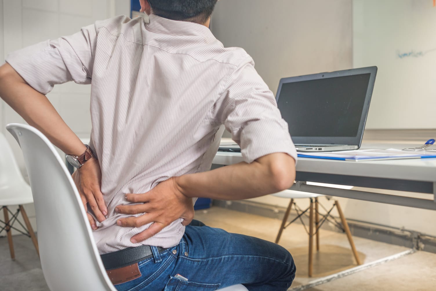 man-holding-his-back-in-pain-on-office-chair